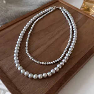 Detailed view of a French retro double-layer pearl necklace displayed on a wooden tray.