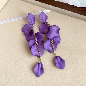 Close-up of bohemian matte purple petal tassel drop earrings on beige texture