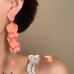 Close-up of bohemian coral pink petal tassel earrings worn on ear