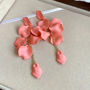 Detail view of Bohemian coral pink matte petal tassel earrings with gold chains