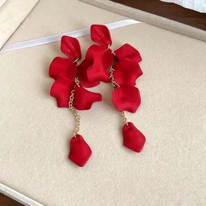 Close-up detail of bohemian matte red petal tassel earrings with elegant gold chains