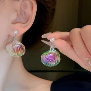 Vista macro de pendientes de concha iridiscente con perlas en la oreja de una modelo asiática.