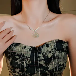 Primer plano de un collar de perlas y concha de sirena en modelo con brillo iridiscente