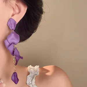 Close-up detail of bohemian purple petal tassel earrings with a matte finish on model