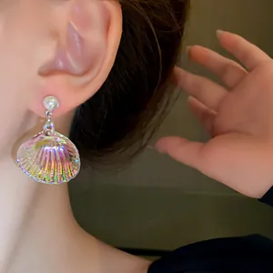 Primer plano detallado de pendientes de concha de sirena irisada con perlas al oído