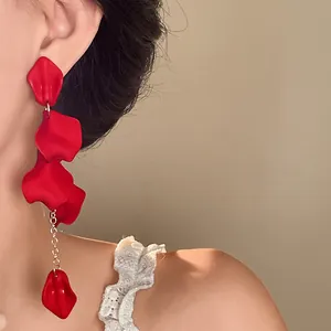 Close-up detail of Bohemian style red petal tassel earrings with silver needle on model.