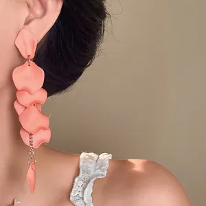 Detailed close-up of matte peach petal tassel earrings worn by a model in soft light.