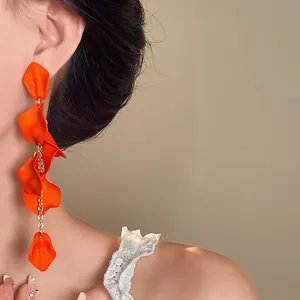 Close-up of vibrant orange petal tassel earrings for a stylish bohemian vacation look.