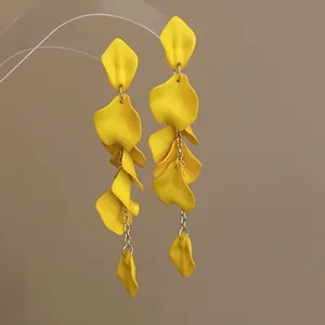 Macro view of bright yellow bohemian style petal tassel earrings with silver needle