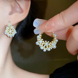 Close-up detail of elegant French-style gold-plated earrings with clustered white pearls.