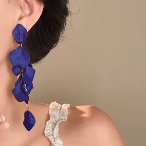 Detail shot of bohemian deep blue matte petal tassel earrings worn by an elegant model