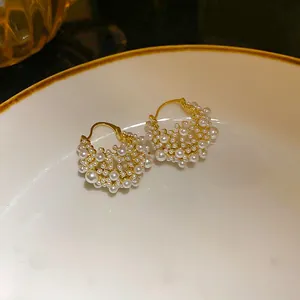 Detailed close-up view of elegant gold-plated hoop earrings featuring clustered white pearls