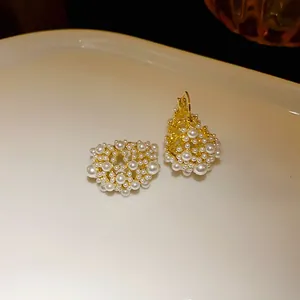 Close-up of elegant gold-plated French style earrings featuring cluster of white pearls