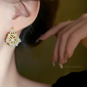 Close-up of elegant gold-plated pearl cluster earrings worn on ear