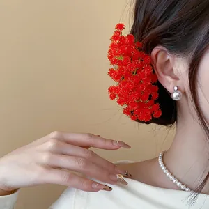 Primo piano di un fermaglio per capelli con fiori in acrilico rosso su una modella