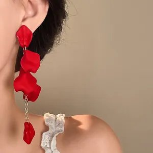 Close-up detail of Bohemian red petal tassel earring worn on ear with gold chain
