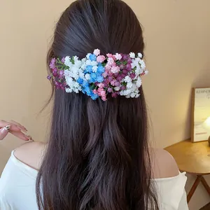 Vista dettagliata di una clip per capelli con fiori in acrilico su lunghi capelli mossi.