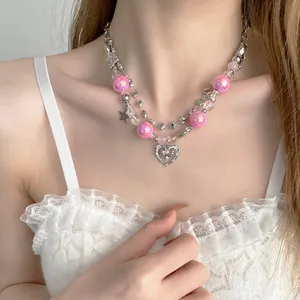 Close-up of double-layer necklace with pink beads and heart pendant worn by model