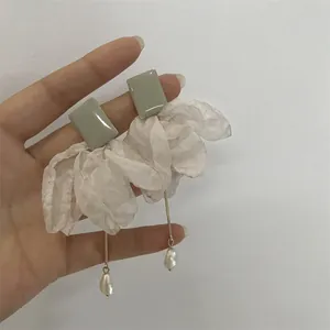 Zoom sur des boucles d'oreilles en argent avec fleurs en organza et perles baroques