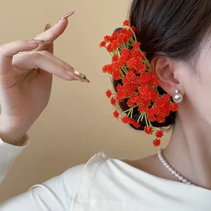 Dettaglio ravvicinato di un fermaglio per capelli con fiori in acrilico rosso su uno chignon