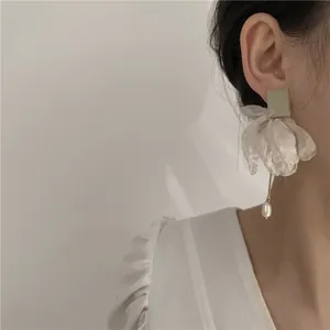 Détail de boucles d'oreilles élégantes en tissu blanc avec perle suspendue sur le modèle