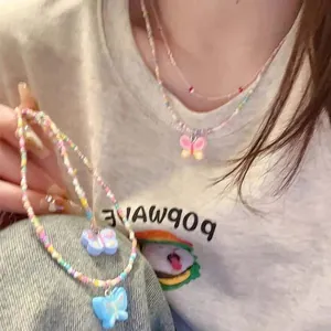 Macro view of colorful beaded necklaces with cute pastel butterfly pendants worn by model