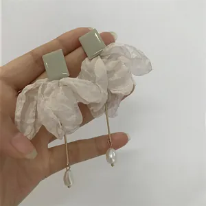 Détail de boucles d'oreilles vert sauge avec fleur en tissu blanc et goutte de perle