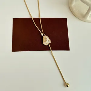 Adjustable gold plated Y-necklace with irregular geometric pendant and ball charm