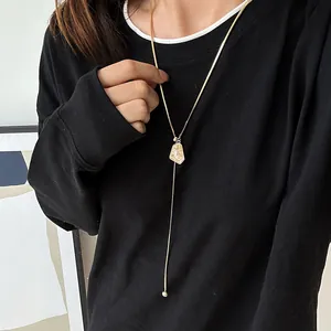 Close-up of a gold-plated irregular adjustable sweater chain on a black sweatshirt