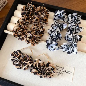 Detailed macro view of chic leopard print fabric flower hoop earrings in a jewelry box