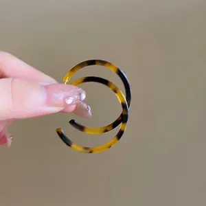 Close-up of hand holding vintage tortoiseshell pattern leopard print hoop earrings.