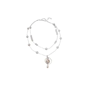 Elegant double-layer pearl necklace featuring a rhinestone Saturn pendant with teardrop detail.