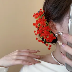 Dettaglio di un fermaglio per capelli a grappolo di fiori in acrilico rosso indossato con stile