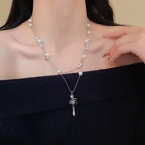 Detail view of the double-layer pearl necklace with a sparkling Saturn pendant