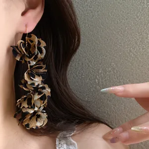 Close-up of leopard print fabric flower petal dangling earrings on a female model.