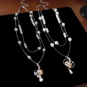 Detailed view of two-layered pearl necklaces with sparkling Saturn orb pendants.