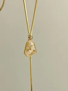 Detailed view of the gold-plated irregular pendant with gold foil accents on a snake chain