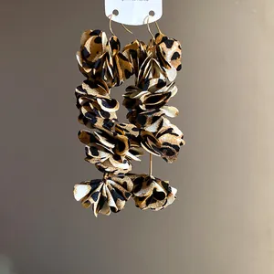 Detailed macro view of layered leopard print fabric flower earrings with gold hooks.