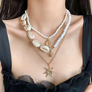 Detailed view of a bohemian three-layered beach necklace set with shells and sun charms