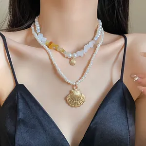 Close-up detail of a double-layer pearl necklace set with elegant golden shell pendants