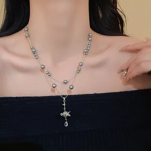 Detailed view of a double-layer necklace featuring grey pearls and crystal Saturn pendant