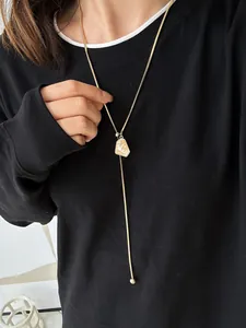 Detail shot of a minimalist gold-plated adjustable Y-necklace on a black sweater