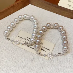 Elegant French style pearl bracelet with zircon flower charms on a linen background texture