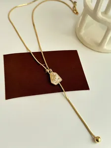 Detailed macro shot of a gold-plated adjustable necklace with an irregular geometric pendant