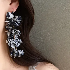 Detailed macro view of leopard print fabric flower drop earrings worn by a female model