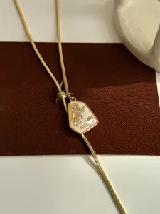Close-up of an adjustable gold-plated necklace with a geometric gold-foil inlay pendant.