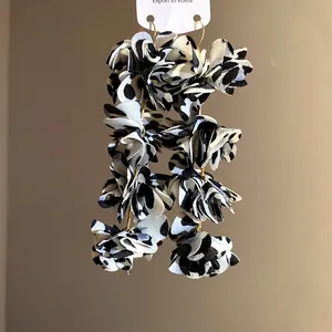 Close-up detail of stylish black and white leopard print fabric flower drop earrings