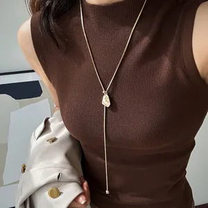 Detail of gold-plated irregular pendant adjustable necklace on brown knit sweater