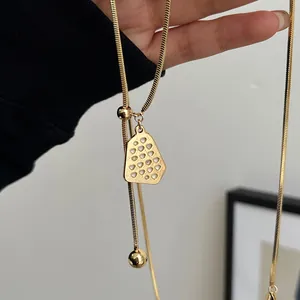 Detail of gold plated adjustable necklace with geometric pendant on a sleek snake chain