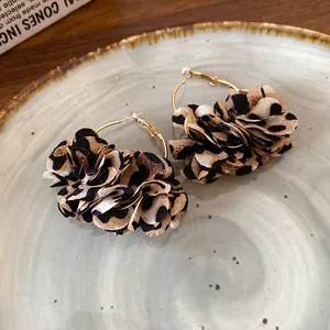 Close-up of leopard print fabric flower hoop earrings on a beige ceramic plate